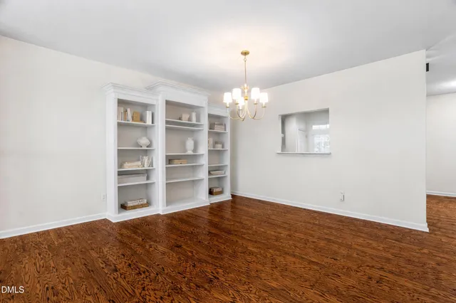 a dining room with wooden floor a chandelier a wooden table and chairs