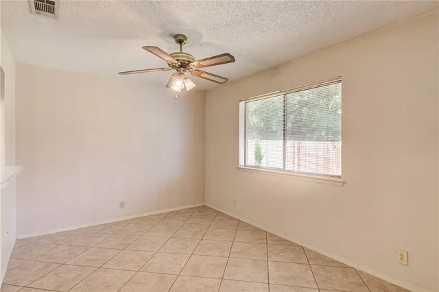 an empty room with a window and a fan