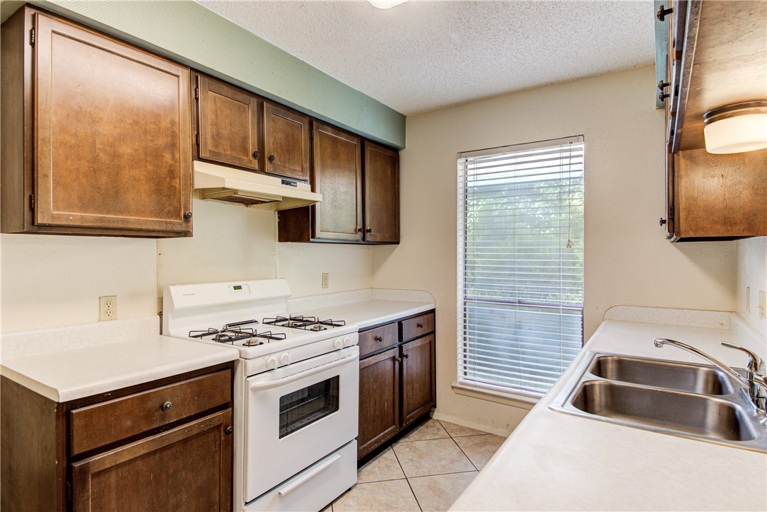 12012 Swallow Drive Austin, TX 78750 - Photo 11 of 33 a kitchen with granite countertop a sink a stove and cabinets