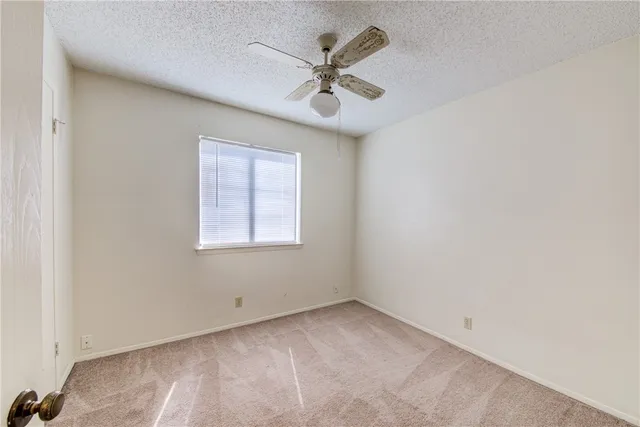 an empty room with a window and a ceiling fan