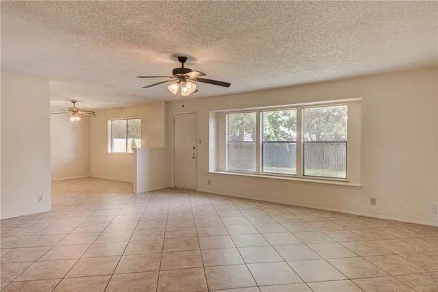 a view of an empty room with a window and kitchen view