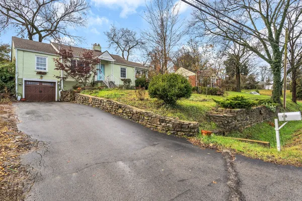a front view of a house with a garden and trees