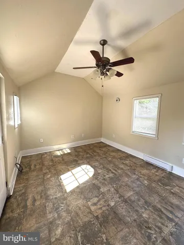 an empty room with a chandelier fan and windows