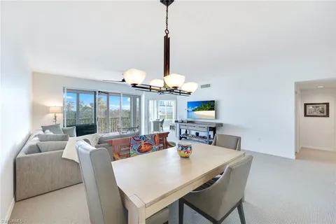 a view of a dining room with furniture a chandelier and a window