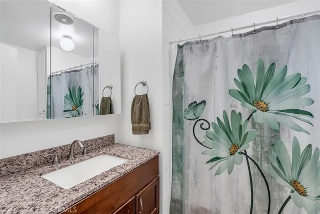 a bathroom with a granite countertop sink a mirror and a shower curtain