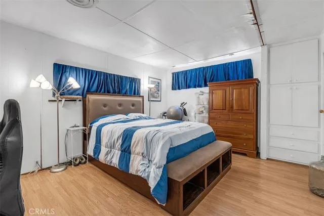 a bedroom with a bed a dresser and a potted plant