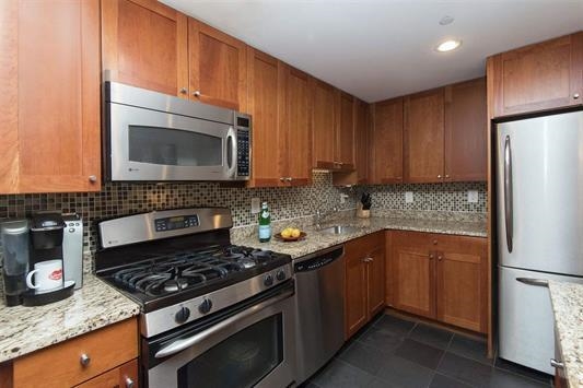 700 Grove Street, Unit 8R Jersey City, NJ 07310 - Photo 2 of 11 a kitchen with stainless steel appliances granite countertop a stove microwave refrigerator and sink