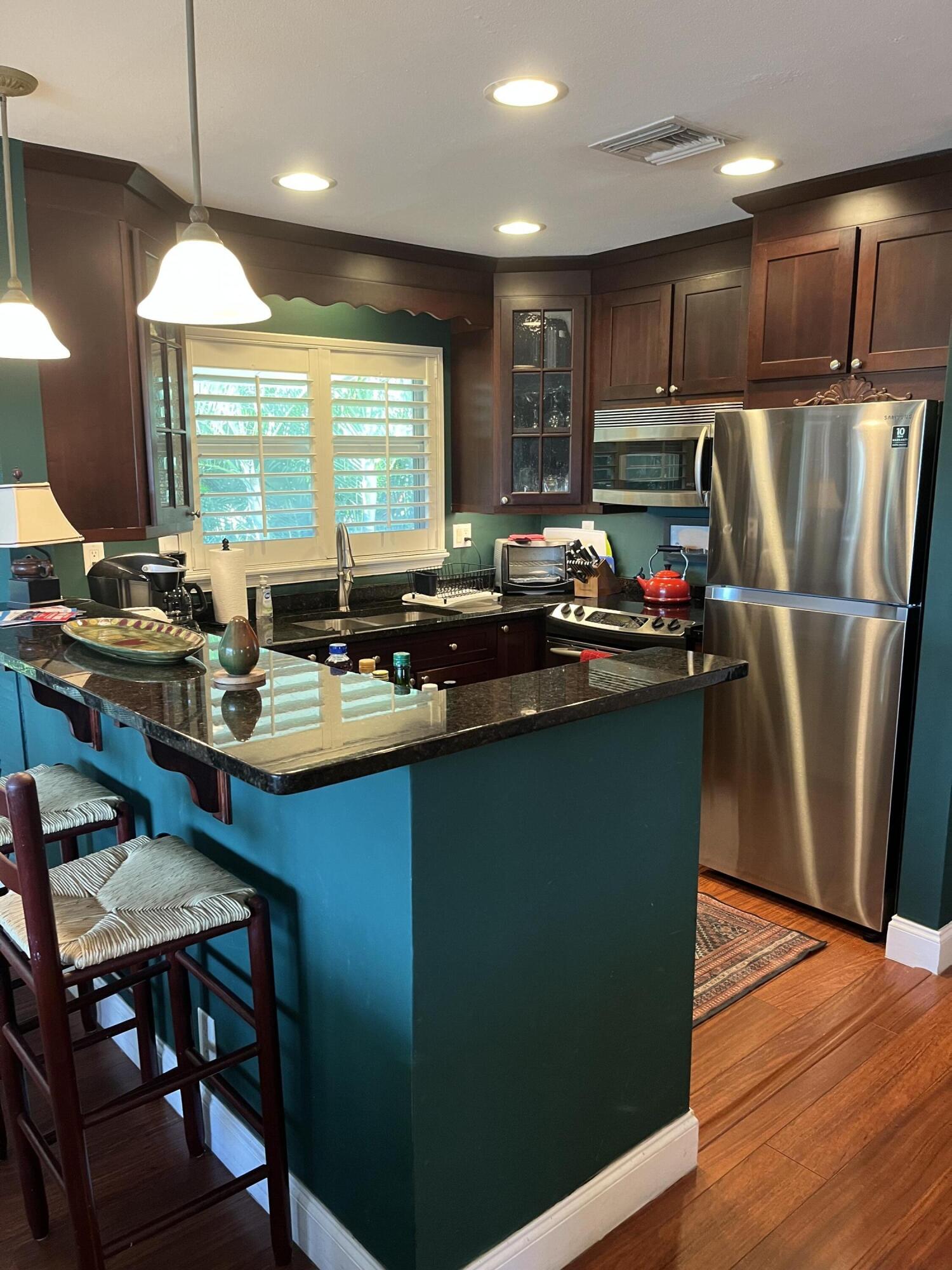 24 Marine Way, Unit 26 Delray Beach, FL 33483 - Photo 6 of 18 a kitchen with kitchen island a sink a stove a refrigerator and chairs