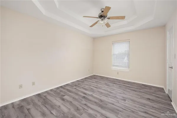 an empty room with wooden floor fan and windows