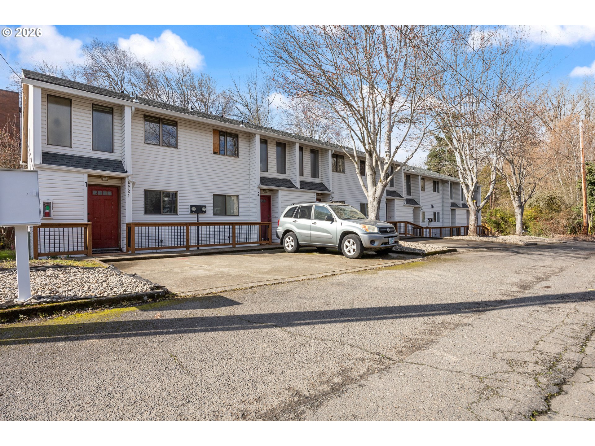 4921 Southwest 59th Avenue, Unit 6 Portland, OR 97221 - Photo 22 of 23 a view of a white house next to a road with large trees