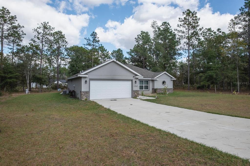 12569 Southwest 73rd Street Ocala, FL 34481 - Photo 1 of 28 a front view of a house with a yard and garage