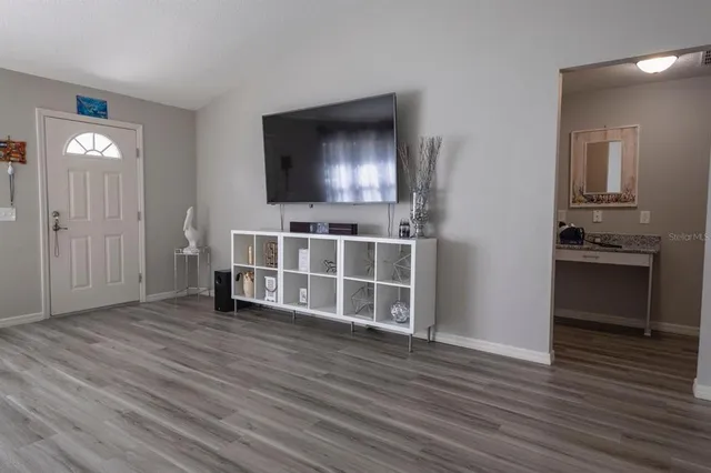 a view of a livingroom with wooden floor and a kitchen