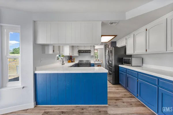 a kitchen with stainless steel appliances granite countertop a sink a stove and a wooden floors
