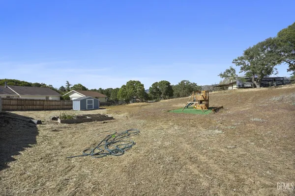 a view of a dry yard with trees in the background