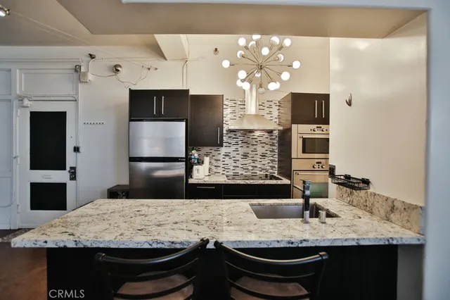 a bathroom with a granite countertop sink a large mirror and a refrigerator