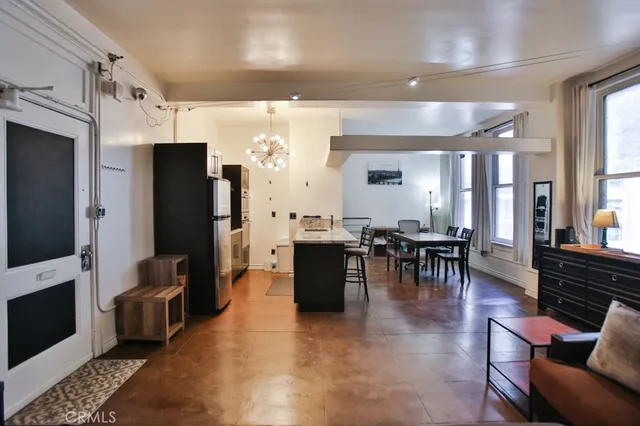 a living room with furniture a table and kitchen view