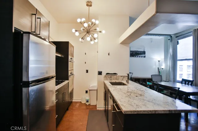 a kitchen with stainless steel appliances granite countertop a sink a refrigerator and a stove