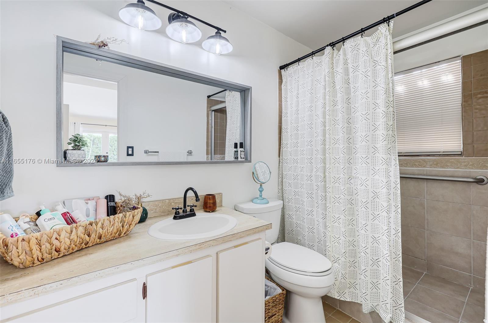 14871 Southwest 156th Street Miami, FL 33187 - Photo 32 of 84 a bathroom with a sink a toilet and shower curtain