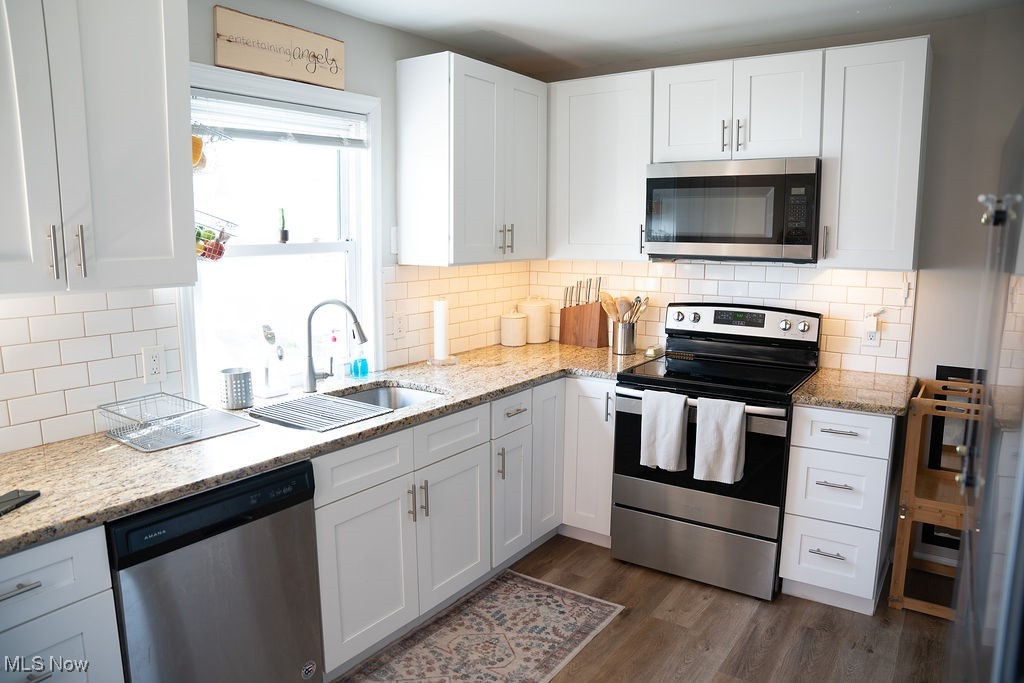 2707 Hearthstone Road Cleveland, OH 44134 - Photo 17 of 49 Kitchen featuring a sink, white cabinetry, tasteful backsplash, stainless steel appliances, and dark wood-type flooring