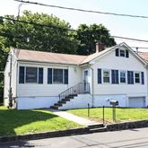 a front view of a house with a big yard and potted plants