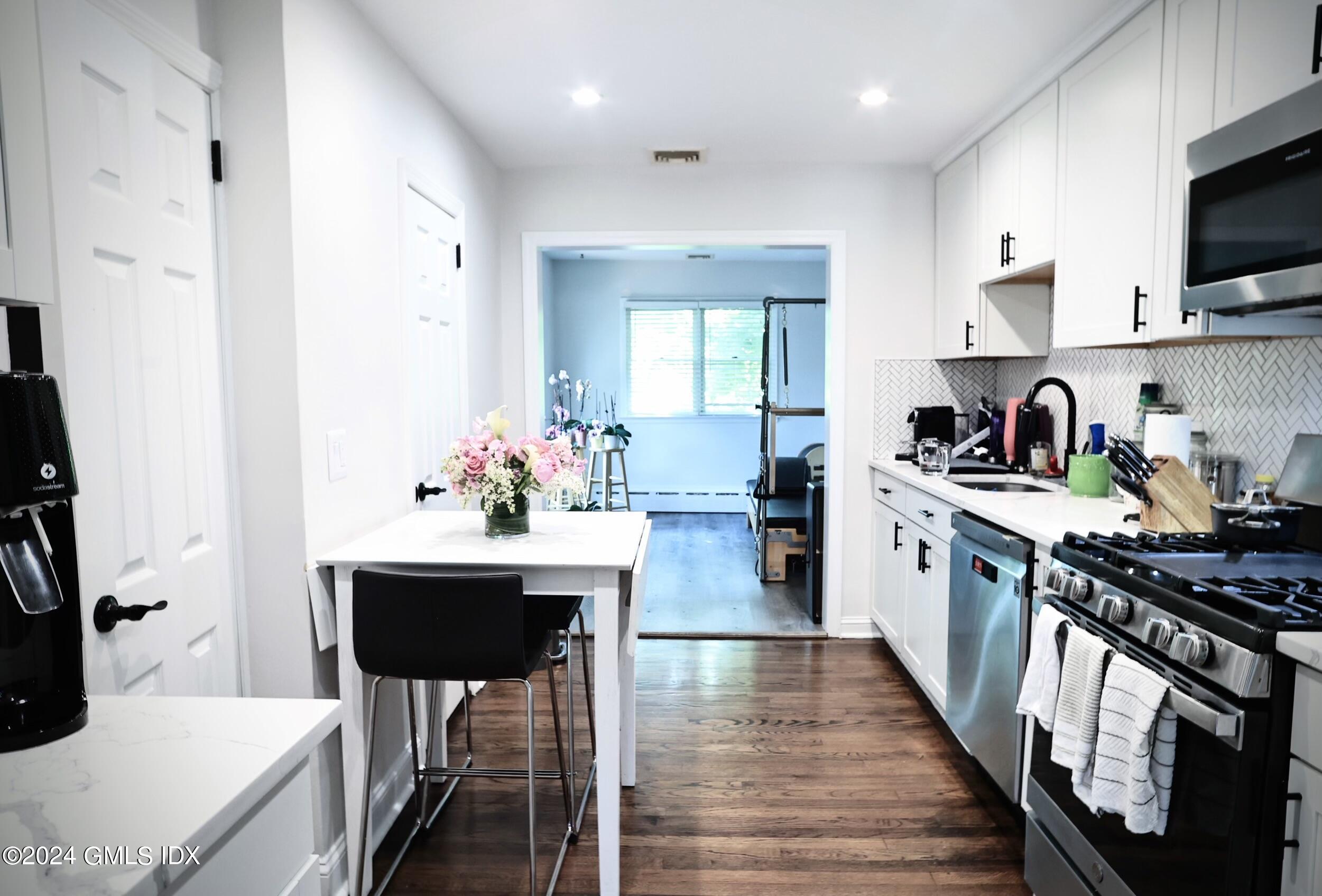 4 Silver Street, Unit B Greenwich, CT 06830 - Photo 7 of 24 a kitchen with stainless steel appliances kitchen island granite countertop white cabinets a sink dishwasher and a stove with wooden floor