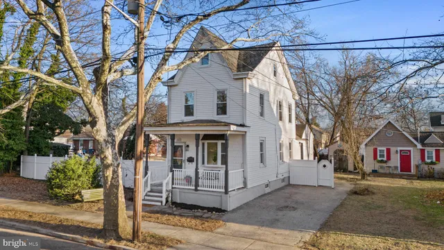 a view of a white house with a large tree