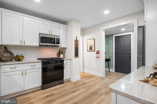 a kitchen with granite countertop a stove top oven a sink dishwasher and a refrigerator with wooden floor