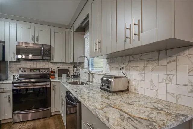 a kitchen with granite countertop cabinets stainless steel appliances and wooden floor