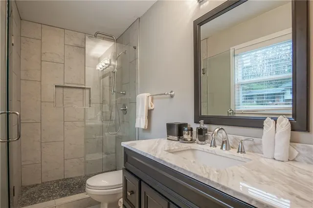 a bathroom with a granite countertop sink a toilet and shower