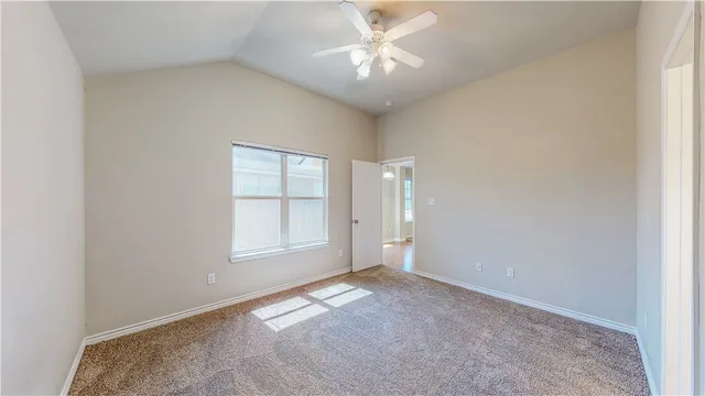 an empty room with a ceiling fan and a window