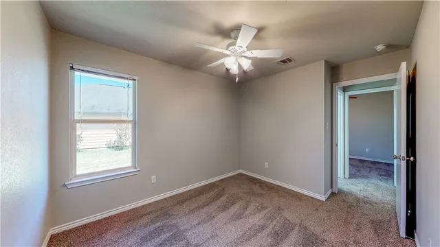 an empty room with windows and fan