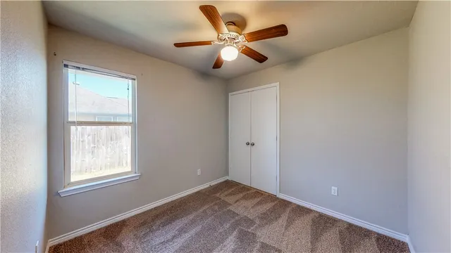 a view of an empty room with window and a ceiling fan