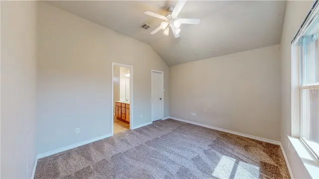 an empty room with a chandelier fan and windows