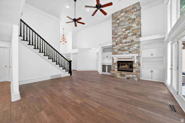 883 East 700 South Springville, UT 84663 - Photo 4 of 59 Spacious living area featuring high ceilings, wood-finish flooring, a stone fireplace with a white mantel, built-in shelving and cabinetry, and multiple ceiling fans
