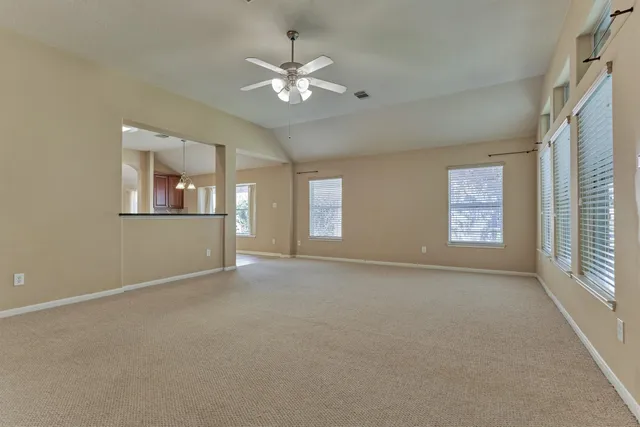 an empty room with windows and chandelier fan