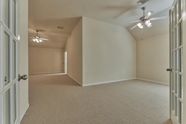 an empty room with a chandelier fan and closet area