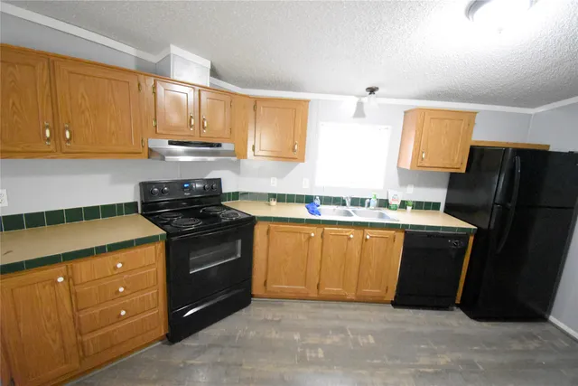 a kitchen with granite countertop a refrigerator stove top oven and sink