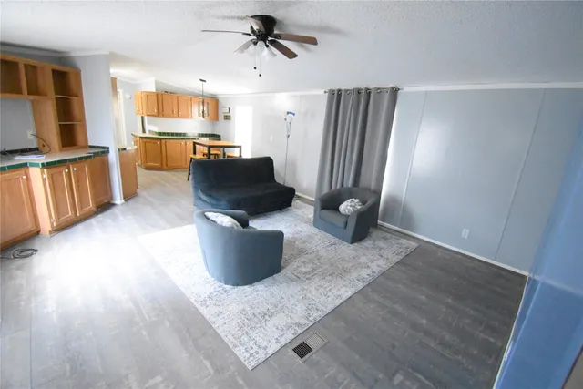 a living room with furniture a flat screen tv and a refrigerator