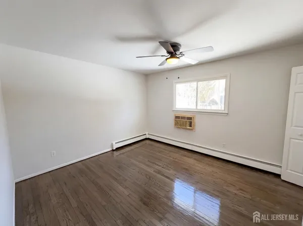 an empty room with wooden floor ceiling fan and windows