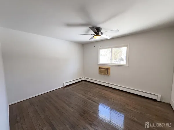 an empty room with wooden floor ceiling fan and windows