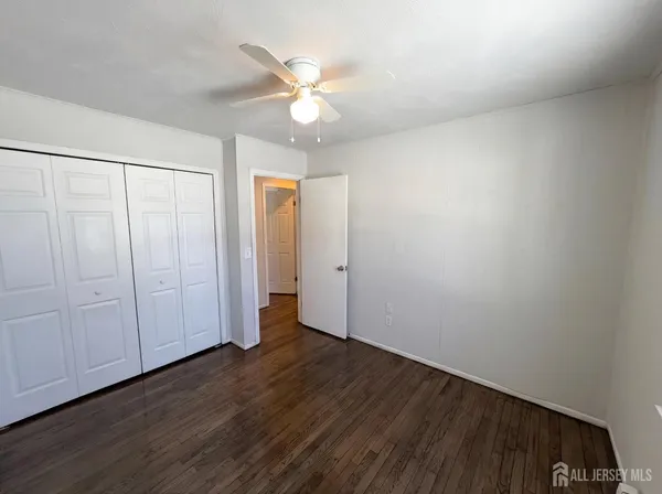an empty room with wooden floor and fan
