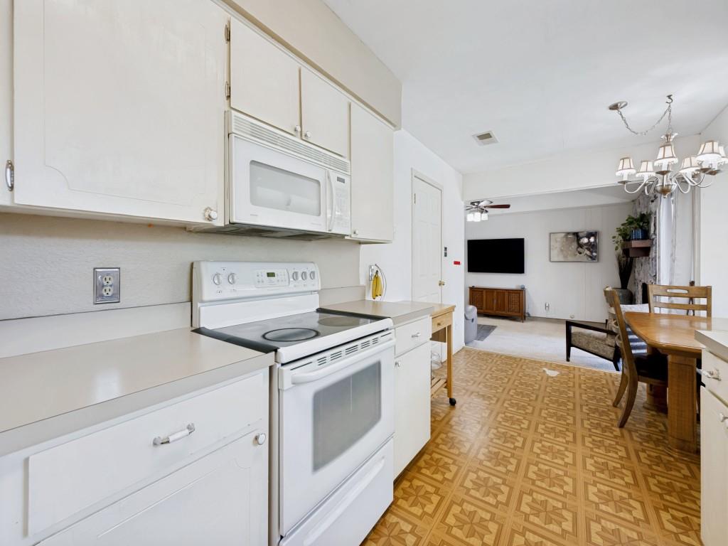 6484 Old Mill Circle Watauga, TX 76148 - Photo 12 of 25 Kitchen with white appliances, white cabinets, light countertops, light flooring, and suspended lighting