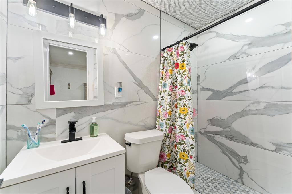 3318 San Marcus Avenue Dallas, TX 75228 - Photo 15 of 18 Bathroom featuring vanity, a marble finish shower, and tile walls