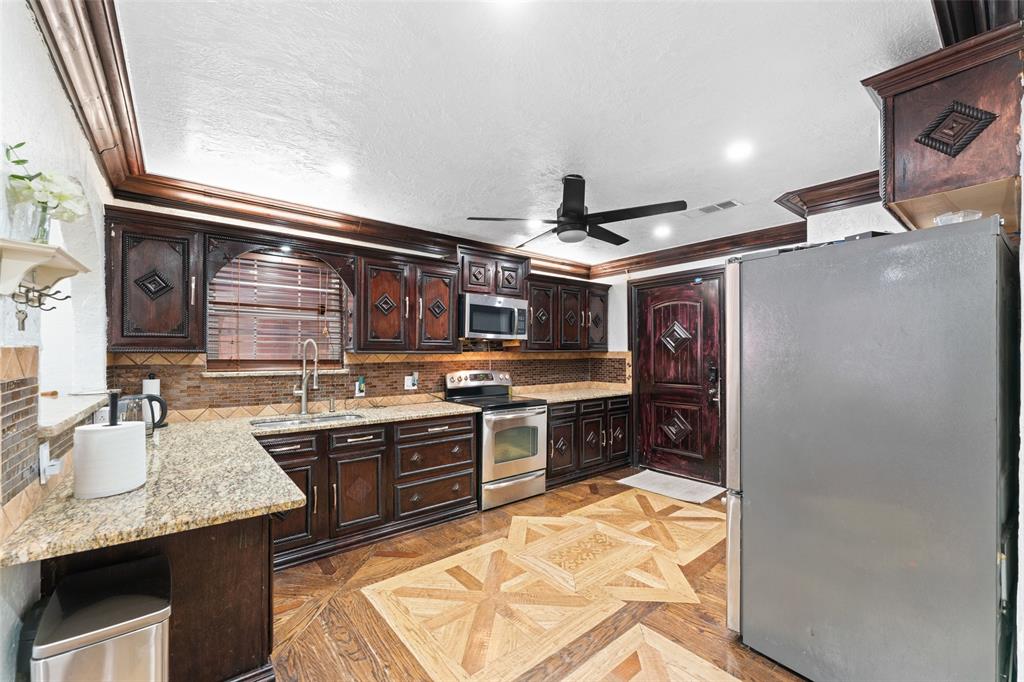 3318 San Marcus Avenue Dallas, TX 75228 - Photo 8 of 18 Kitchen with stainless steel appliances, dark wood finish cabinetry, ornamental molding, parquet floors, and light stone countertops