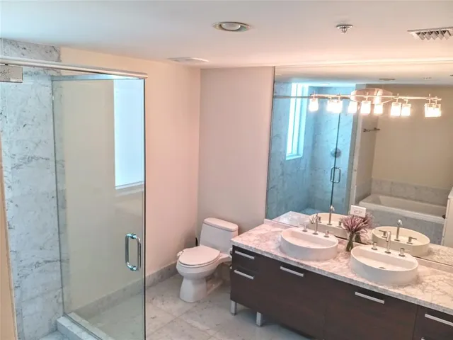 a bathroom with a granite countertop sink a toilet and shower