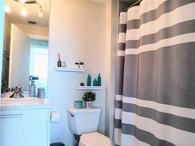 a bathroom with a sink a toilet a shower curtain