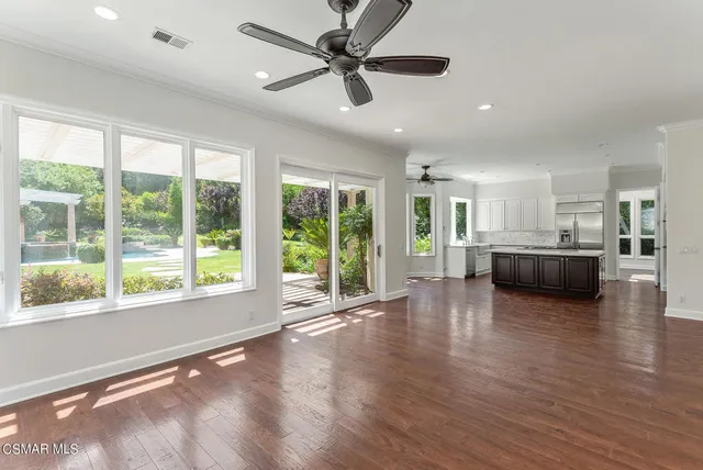 a view of a livingroom with furniture wooden floor a ceiling fan and a kitchen view