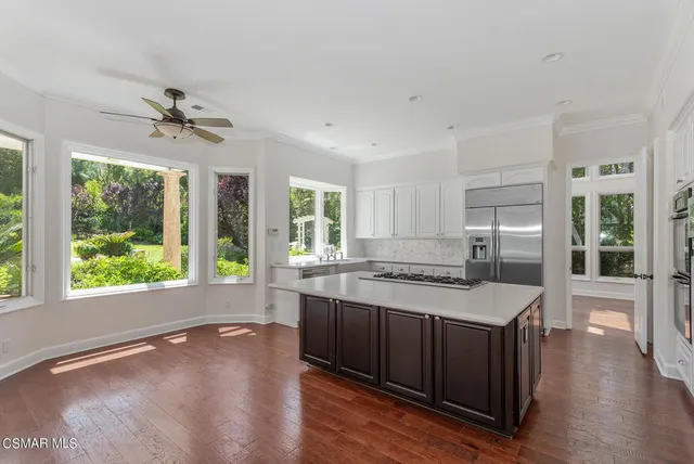 a kitchen with a stove a sink a counter top space and living room view