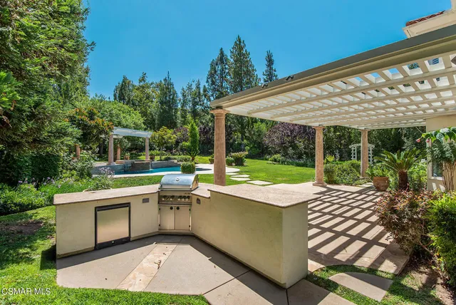 a view of a patio with a table and chairs under an umbrella next to a yard