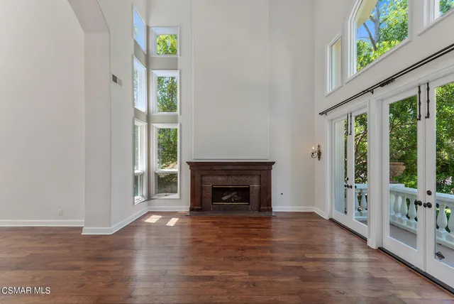 an empty room with wooden floor fireplace and windows